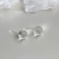 Detailed close-up of minimalist transparent crystal ball stud earrings, elegant and clear glass design. - Clear White