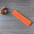 Gros plan détaillé du bandeau de yoga élastique orange vif montrant la texture douce. - Orange