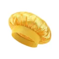 Close-up detail of the soft yellow satin sleep bonnet, showing smooth fabric and elastic band. - Yellow