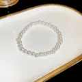 Exquisite pearl bracelet detail showing smooth round white beads on a elegant white and gold tray. - 6mm Bead Style / White