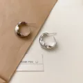 Minimalistische silberne Metall-Creolen mit unregelmäßiger Textur, schicker Damenschmuck. - Vergoldetes Silber
