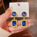 Nahaufnahme von Vintage goldfarbenen geometrischen Ohrringen mit auffälligen blauen Steinen. - Blau
