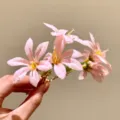 Nahaufnahme des rosa Stoffblumen-Haarclips mit Wassertropfen, zeigt weiche Textur. - Haarstab / Goldfarben Rosa