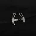 Closeup of asymmetrical bow earrings featuring sparkling zircon and smooth metal design. - Asymmetric Bowknot Style