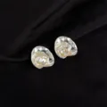 Close-up detail of irregular shell-shaped ear clips with pearlescent and gold flake accents. - Ruffle Pearl Style