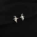 Detailed close-up of shiny silver star ear clips with sparkling cubic zirconia on black. - Zirconia Star Style