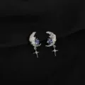 Detailed close-up of silver moon and star earrings featuring sparkling blue crystals and pearls. - Zircon Moon