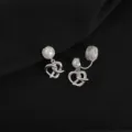 Close-up shot of silver clip-on earrings featuring a pearl top and twisted knot pendant. - Pretzel Style