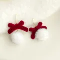 Nahaufnahme der süßen roten Beflockungs-Schleife und weißen Bommel-Ohrringe, weiche Textur. - Schleife & Fellknäuel