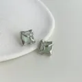 Close-up of minimalist liquid-shaped silver earrings with micro-inlaid zircon and green stone. - 2537 Transparent Green Glass Cat's Eye