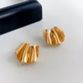 Primo piano di orecchini a lobo metallici piegati con design a superficie liscia. - Oro Curvo (4339)