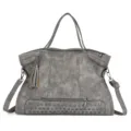 Detailed view of gray PU leather tote bag with metal studs and cute tassel charm. - Gray