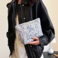 Detail view of textured cosmetic pouch, portable travel makeup storage bag with small label. - Stone Pattern Light Blue