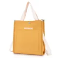 Close-up of yellow canvas tote bag with front pocket, white straps, and detailed view. - Yellow