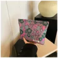 Detail shot of a floral cosmetic bag with embossed botanical pattern, stylish clutch design. - Jacquard Purple Flowers