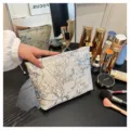 Detailed view of embossed floral cosmetic bag, portable travel toiletry storage pouch. - Gold Wire Blue Plum
