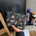 Dettaglio in primo piano della trousse in tessuto nero con motivi di farfalle tessute. - Farfalla Nera