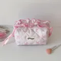 Vue détaillée de la trousse de toilette matelassée rose avec imprimé floral et ruban. - Rose