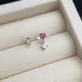 Nahaufnahme Detail der asymmetrischen Herz Pfeil und gruenen Zirkon Stecker Ohrringe. - Cupido Herz Stil / asymmetrisch / Gold