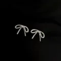 Detailansicht silberner schleifenförmiger Clip-Ohrringe, elegantes Metall-Design ohne Ohrlöcher. - Schleife Clip / Silber