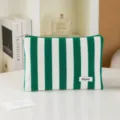 Detail view of green and white striped cosmetic pouch, zipper closure, textured fabric. - Green and White Striped
