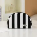 Detailed view of black and white striped cosmetic bag on white table in chic interior setting. - Black & White Stripes