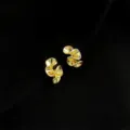 Nahaufnahme von stilvollen gedrehten goldenen geometrischen Ohrringen auf schwarzem Grund. - Doppelschichtige Clip-Ohrringe - Künstlerische Falten