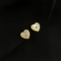 Detaillierte Nahaufnahme eleganter herzförmiger Muschelohrringe mit goldenen Perlenrändern. - Doppelschicht-Ohrclips - Natürliches Muschel-Herz