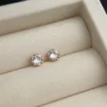 Nahaufnahme der minimalistischen roségold vergoldeten Zirkon Ohrstecker in einer sanften Box. - Großer Runder Zirkonia Stil / Gold