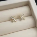 Nahaufnahme der zarten 14K vergoldeten Kreuz Ohrstecker mit funkelnden Zirkonia Steinen. - Kreuz Zirkonia Stil / Gold