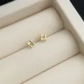 Detailaufnahme minimalistischer goldener geometrischer Ohrstecker in einer eleganten Schmuckbox. - Goldener Quadratischer Würfel Stil / Gold