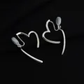 Modische asymmetrische Herz Clip-Ohrringe mit Metall-Finish für ungebohrte Ohren. - Baumelndes Herz