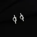Nahaufnahme Detailansicht der eleganten Silberknoten-Ohrringe, minimalistisch gearbeitet. - Knoten