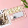 Clear PVC cosmetic bag with textured chenille BEACH letters detail close up display - Beach Vibes / Beige