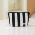 Close-up detail of black and white striped cosmetic makeup bag with zipper and brand label. - Black & White Stripes