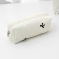 White quilted pencil case makeup bag with cute black bow embroidery, minimalist storage detail view. - White