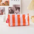 Close-up detail of the glossy striped cosmetic pouch with tassel and clean stitching. - Small Orange Pink