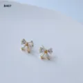 Mini-Detailaufnahme von minimalistischen Zirkon-Schleifen-Ohrsteckern in vergoldetem Design. - Schleifenstil (B-407)
