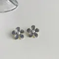Close-up of grey floral oil-drop earrings with pearl center and sleek gold-tone rim detail. - Off-White