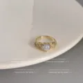 Detaillierte Nahansicht eines filigranen vergoldeten Zirkonia-Herzrings mit funkelnden Steinen. - Offen Verstelbar / Hellblaues Herz-Design (C-350 Dick Echtgold-vergoldet)