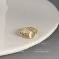Detailaufnahme des verstellbaren goldenen offenen Rings mit ovalem weißem Stein, hohlem Design. - Offen Verstelbar / Hohlkreuz-Opal-Stil (Dick echtvergoldet)