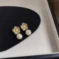 Detailaufnahme von eleganten goldenen Blumen-Ohrsteckern mit hängenden Süßwasserperlen. - Blume Perle Stil (C-715)