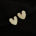 Detailansicht von unregelmäßigen cremefarbenen Herz-Ohrclips mit goldenem Rand. - Emaille Herz