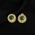 Nahaufnahme Detail von vintage Stil gold texturierte runde Clip-Ohrringe mit gruenem Schmuckstein. - Retro Geometrisch