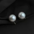 Nahaufnahme detailreicher eleganter Clip-Perlenohrringe mit goldfarbenem Metallglanz. - Zendomah Glasperle Ohrclip / 14mm / Grau