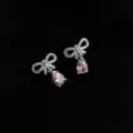 Detailed close-up shot of sparkling rhinestone bow earrings with delicate pink pear-cut drop stones. - Double Layer Clip-On Earrings / Zircon Bowknot