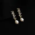 Detailansicht eleganter vergoldeter Ohrringe mit funkelnden Zirkonen und Perlen. - Zirkonia - Vergoldete Mosquito-Spulen-Ohrclips