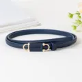 Gros plan sur la ceinture fine en cuir PU bleu foncé avec boucle dorée en forme de fer à cheval. - Bleu marine