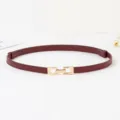 Vue de détail de la fine ceinture femme en cuir bordeaux avec boucle dorée, accessoire rétro. - Café