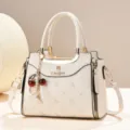 Elegant cream white top-handle handbag with stylish cherry pearl pendant and gold hardware. - Off White